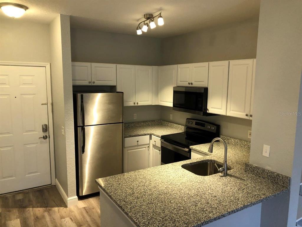 831 Camargo Way, Unit 302 Altamonte Springs, FL 32714 - Photo 3 of 28 a kitchen with granite countertop a refrigerator a stove and a sink