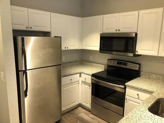 a kitchen with a refrigerator stove and white cabinets