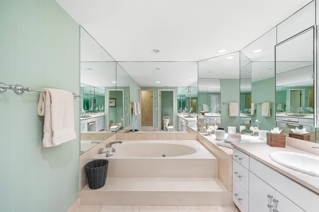 a large white tub sitting in a bathroom next to a large window