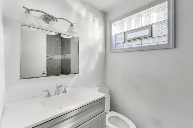 a bathroom with a toilet sink vanity and mirror