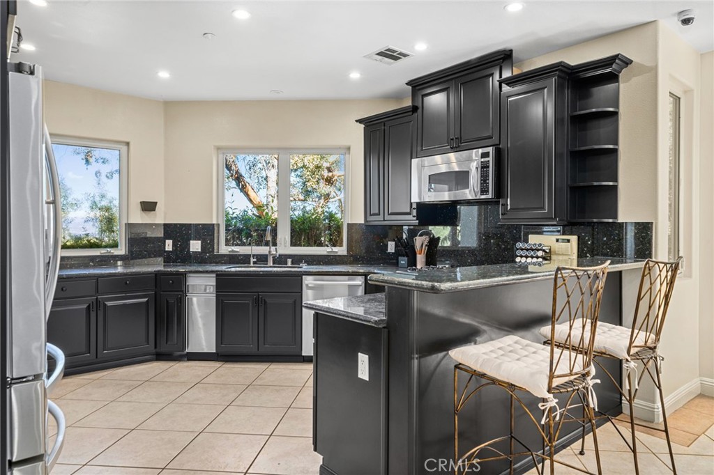 24806 Carlos Place Newhall, CA 91321 - Photo 11 of 56 a kitchen with stainless steel appliances granite countertop a sink stove and refrigerator