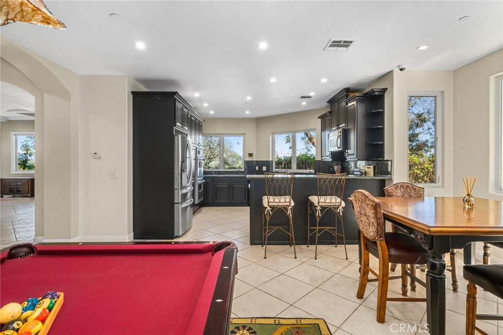 24806 Carlos Place Newhall, CA 91321 - Photo 40 of 56 a kitchen with stainless steel appliances kitchen island granite countertop a dining table chairs and a refrigerator