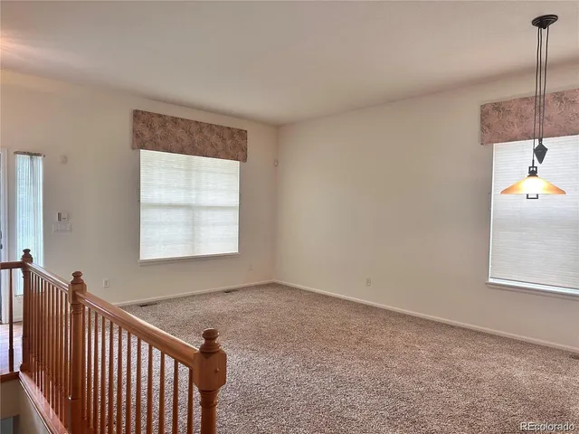 a view of a hallway to a bedroom with wooden floor and windows