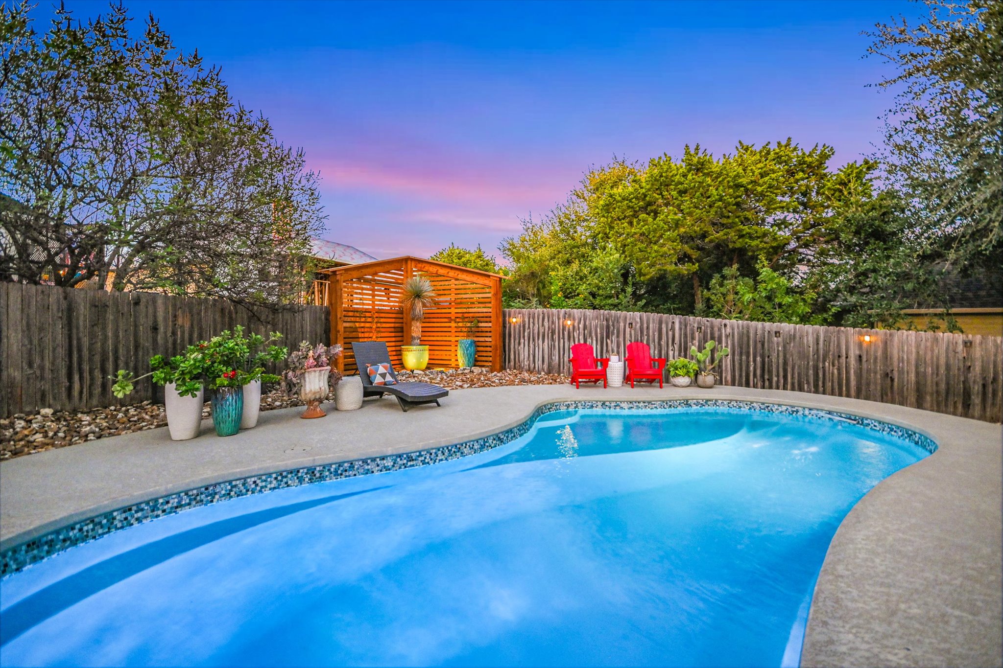 36 Ridgewood Circle Wimberley, TX 78676 - Photo 2 of 30 Mature trees and a privacy fence frame the inviting in-ground swimming pool.