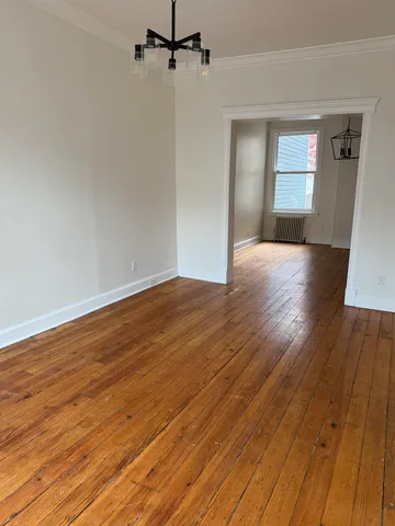 a view of empty room with wooden floor and fan