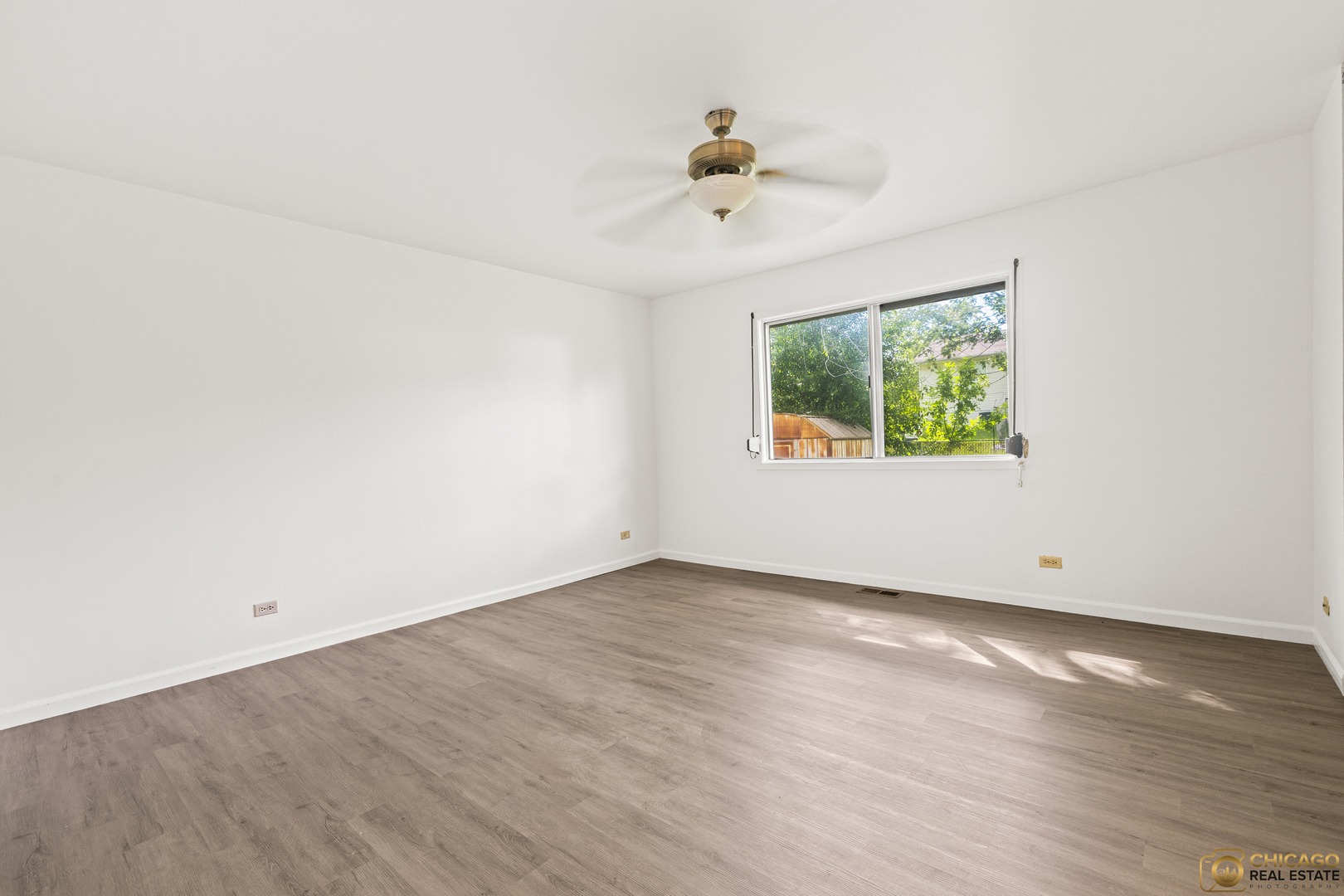 142 Cloverleaf Road Matteson, IL 60443 - Photo 12 of 22 an empty room with wooden floor chandelier fan and windows