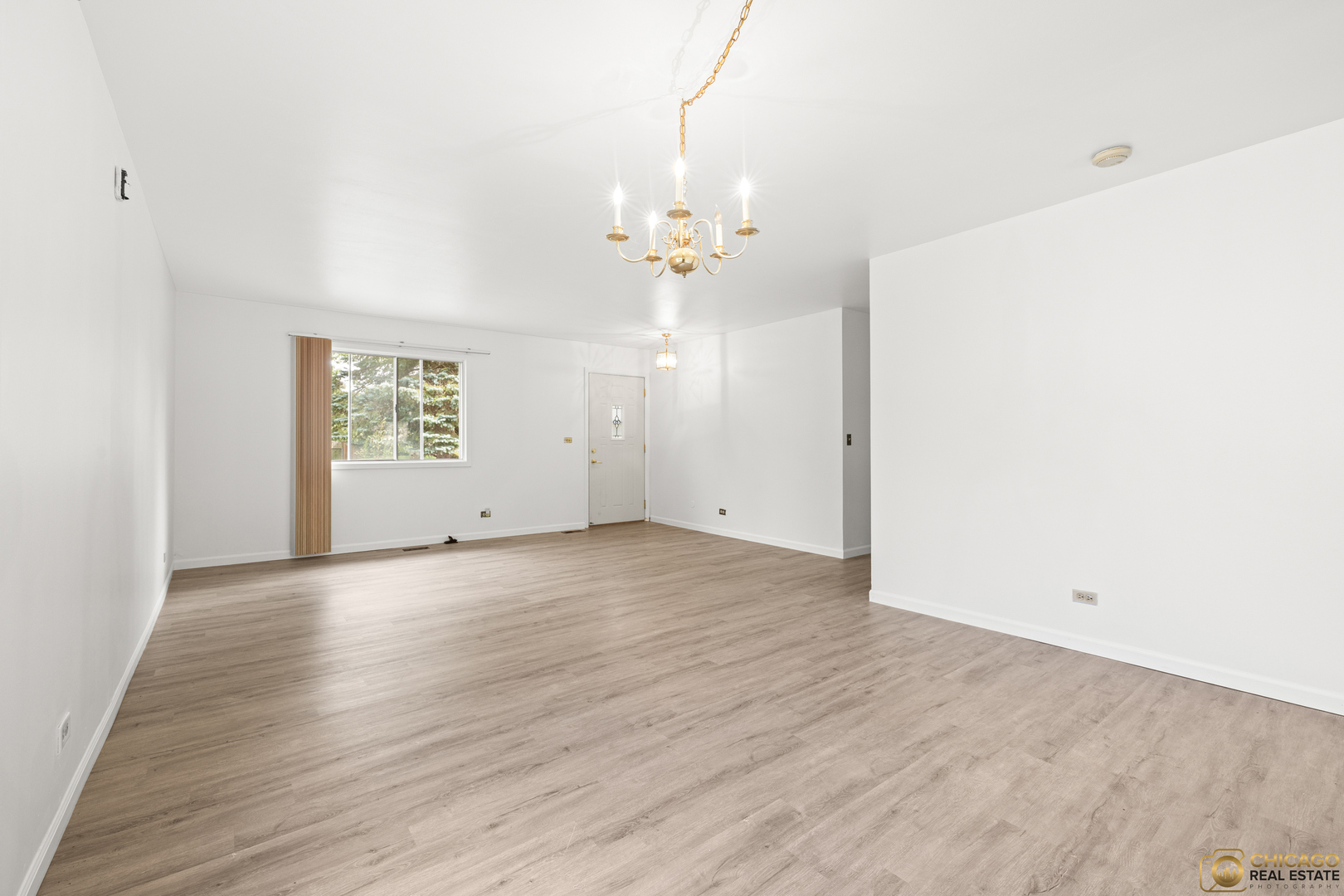 142 Cloverleaf Road Matteson, IL 60443 - Photo 4 of 22 an empty room with wooden floor chandelier fan and windows