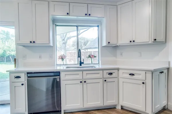 a kitchen with white cabinets and a window