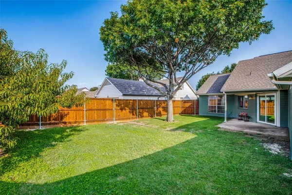 a view of house with a big yard and large trees