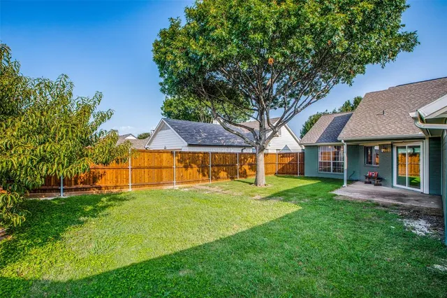 a view of house with a big yard and large trees