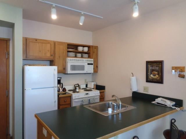 129 River Run Road, Unit 8036 Keystone, CO 80435 - Photo 4 of 20 a kitchen with a refrigerator a stove a sink and white cabinets with wooden floor