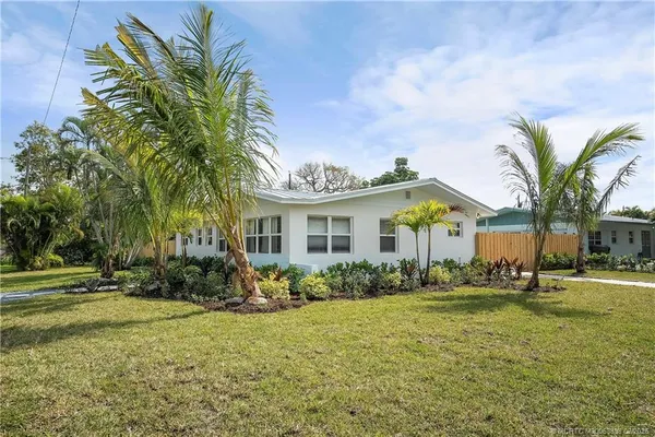 a view of a house with a yard and palm trees