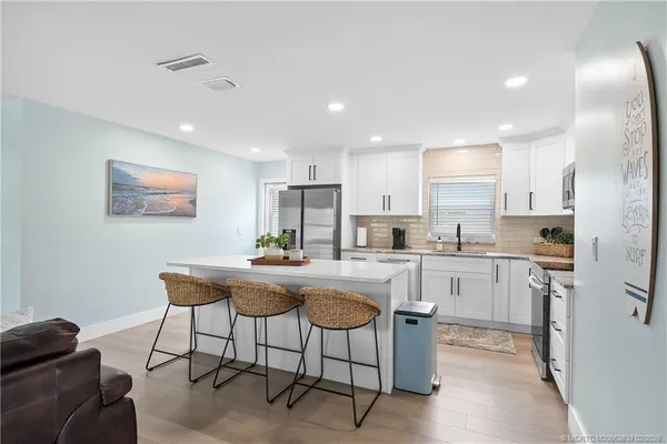 a kitchen with stainless steel appliances granite countertop a sink a stove a refrigerator cabinets and a dining table