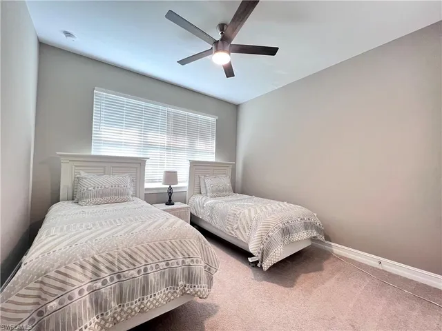 a bedroom with two beds and a ceiling fan