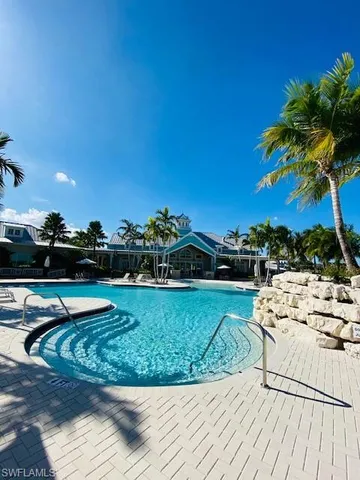 a view of a swimming pool with a lounge chair and palm trees