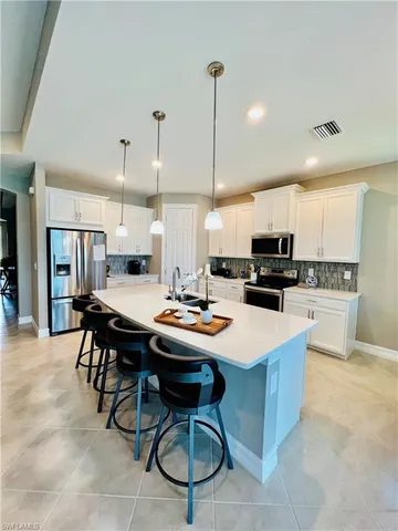 a kitchen with stainless steel appliances kitchen island granite countertop a table chairs sink and cabinets
