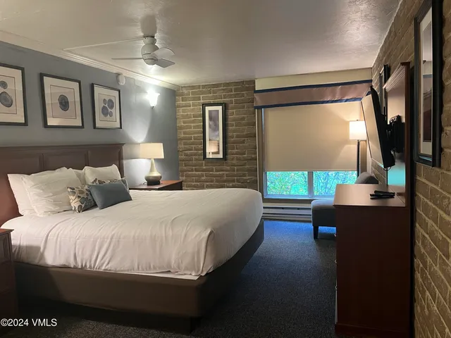 a bedroom with a large bed and a flat tv screen on dresser