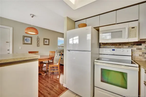 a kitchen with a refrigerator a stove top oven a dining table and chairs with wooden floor