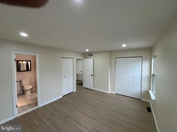 a view of a hallway with wooden floor and a bathroom