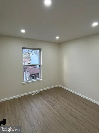 an empty room with wooden floor and window