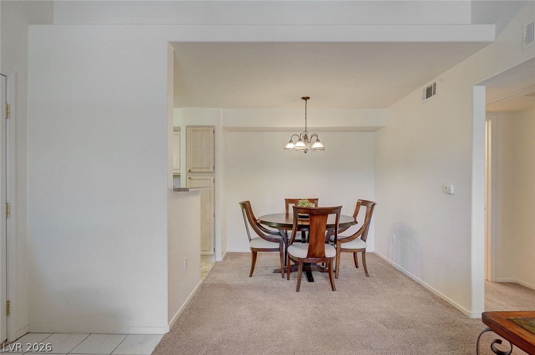 555 East Silverado Ranch Boulevard, Unit 2124 Las Vegas, NV 89183 - Photo 9 of 47 A well-lit dining area featuring a classic chandelier and comfortable carpeted flooring.