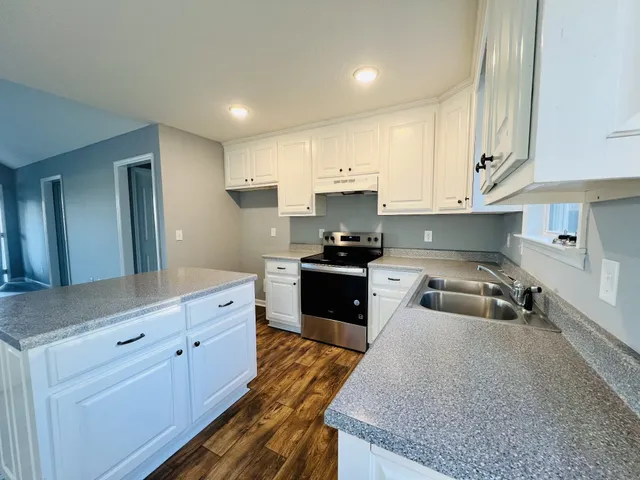 a kitchen with granite countertop a sink stainless steel appliances and cabinets