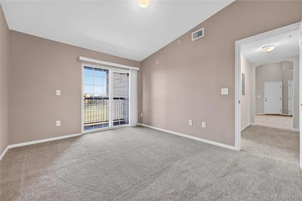 a view of an empty room with window and kitchen