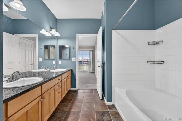 a spacious bathroom with a granite countertop sink mirror and a bathtub
