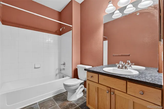 a bathroom with a granite countertop sink a toilet and shower