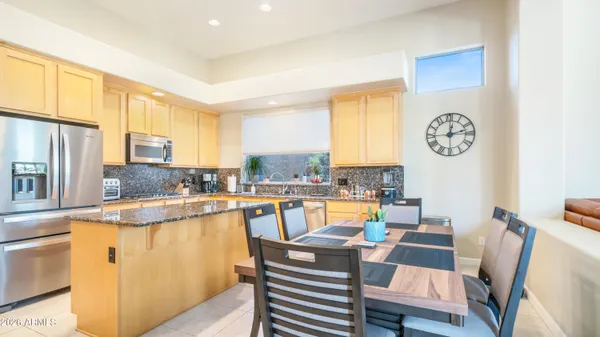 a view of a kitchen with kitchen island granite countertop a sink cabinets and stainless steel appliances