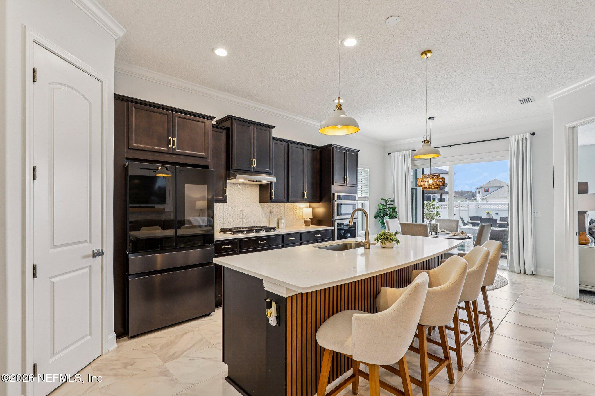 84 Firecrest Drive St. Augustine, FL 32092 - Photo 22 of 72 a kitchen with stainless steel appliances granite countertop a stove a refrigerator a sink a dining table and chairs