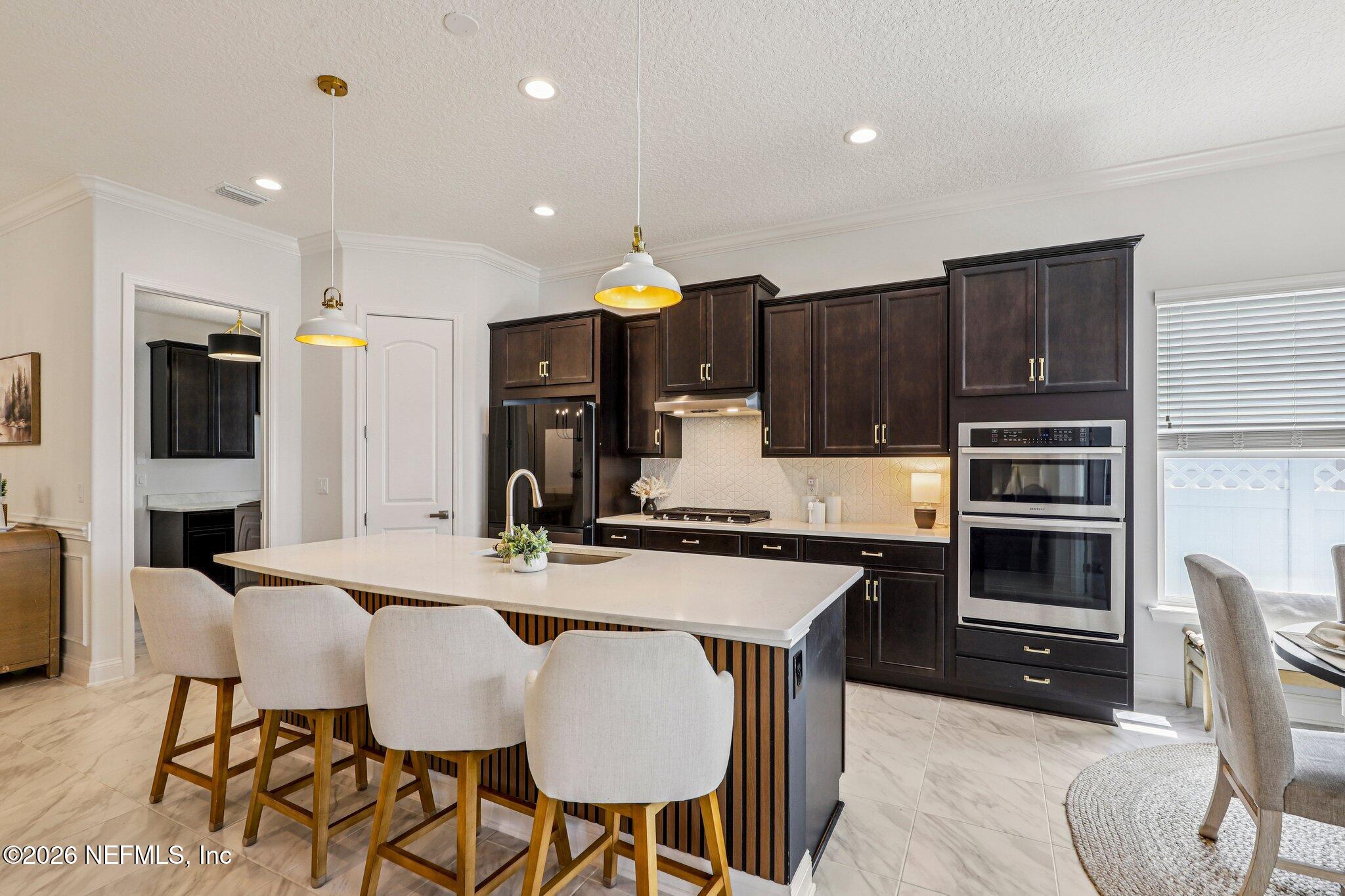 84 Firecrest Drive St. Augustine, FL 32092 - Photo 23 of 72 a kitchen with stainless steel appliances kitchen island granite countertop a stove a sink a refrigerator with a dining table and chairs