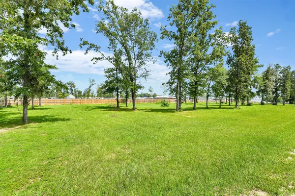 a view of grassy field with benches and trees all around