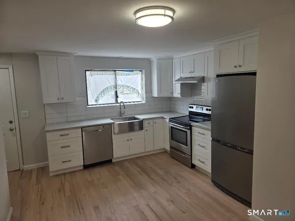 a kitchen with granite countertop white cabinets and stainless steel appliances