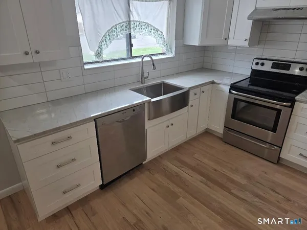 a kitchen with granite countertop a sink cabinets and stainless steel appliances