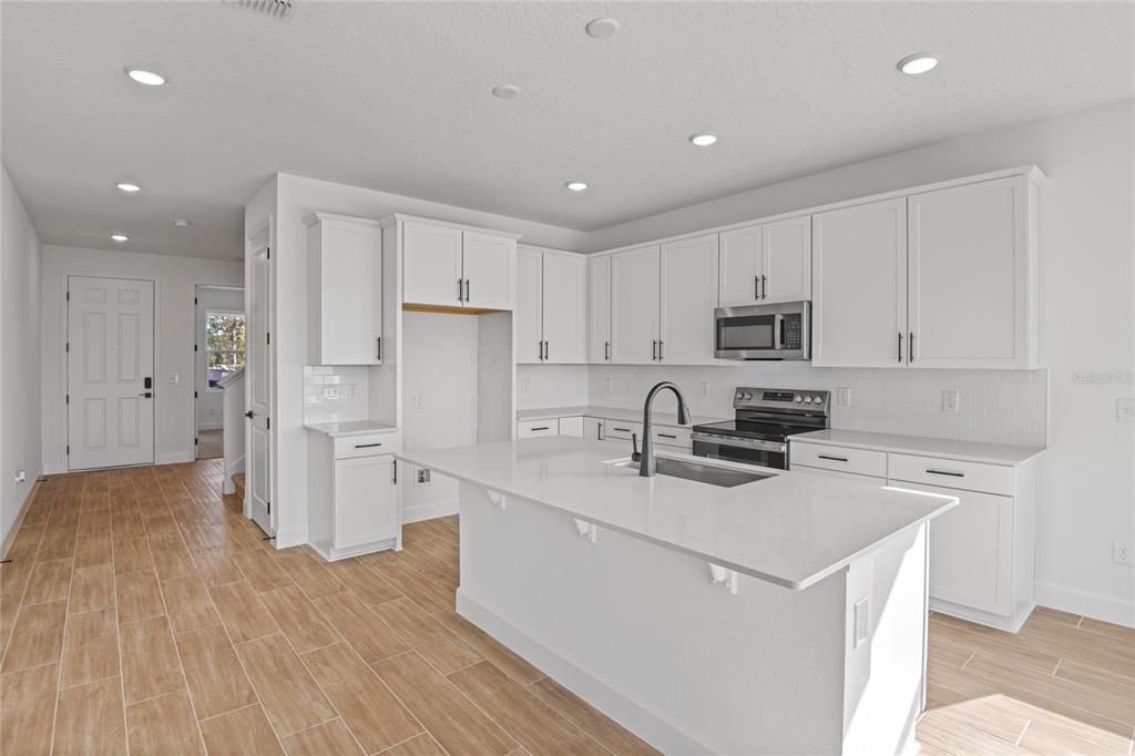 151 Waterstone Loop Tavares, FL 32778 - Photo 5 of 20 a kitchen with a sink a stove a refrigerator a white cabinets and wooden floor