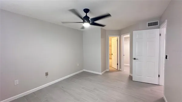 an empty room with wooden floor ceiling fan and windows