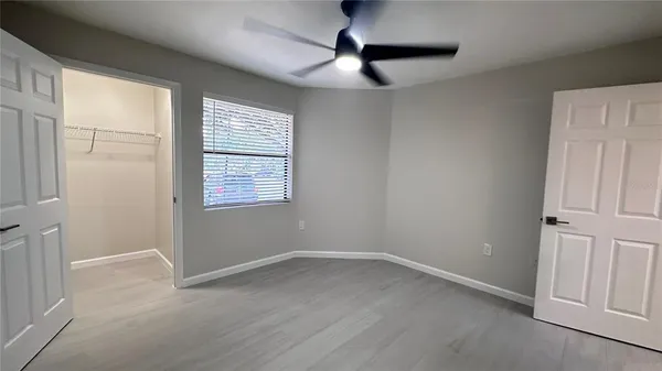 an empty room with windows and fan