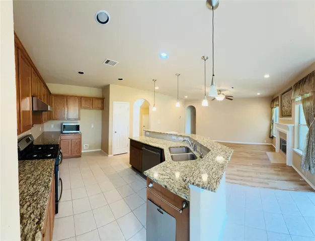 a large kitchen with kitchen island a stove a sink a counter top space and cabinets