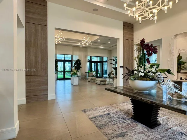 a view of swimming pool that has lawn chairs with plants and palm trees