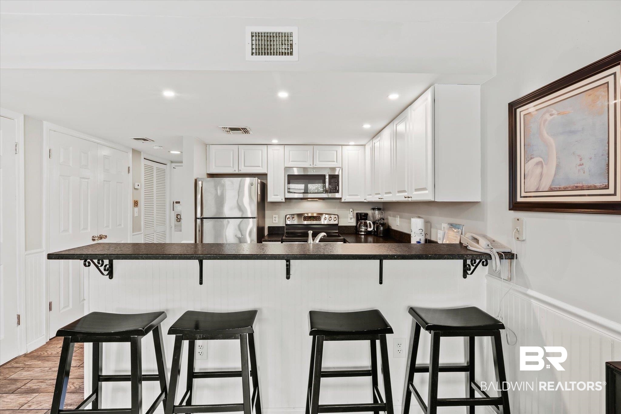 497 Plantation Road, Unit 1164 Gulf Shores, AL 36542 - Photo 6 of 20 Kitchen with white cabinetry, a kitchen bar, stainless steel appliances, kitchen peninsula, and light hardwood / wood-style floors