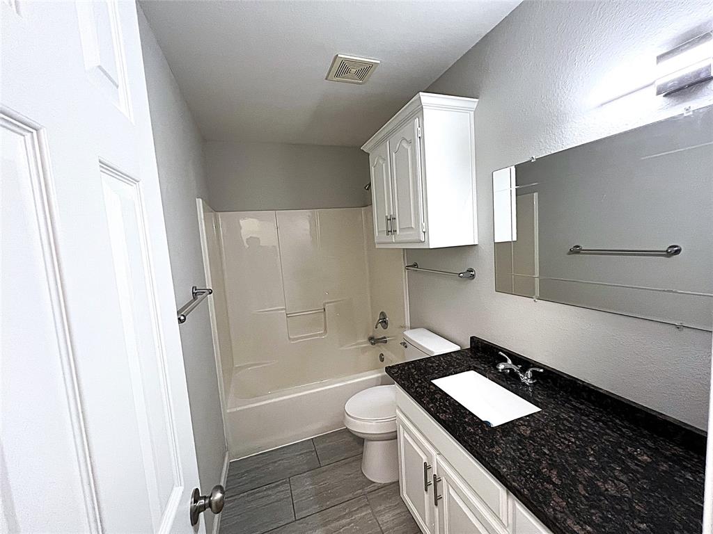 902 Mack Place Denton, TX 76209 - Photo 11 of 11 a bathroom with a granite countertop toilet a sink and a bathtub