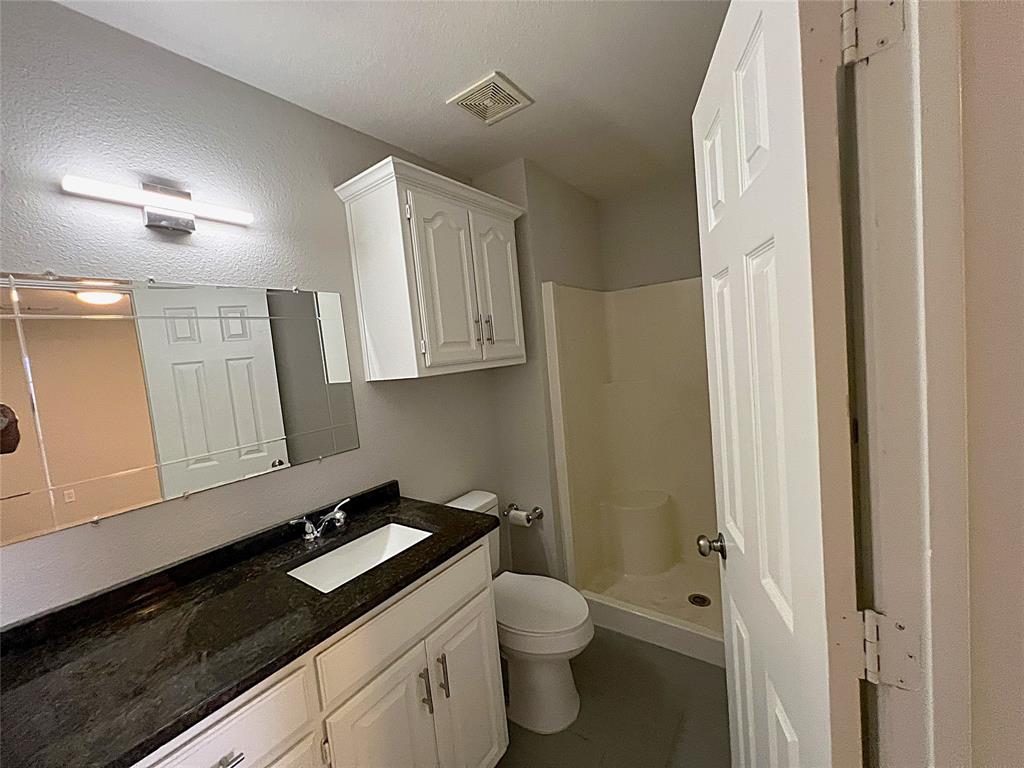 902 Mack Place Denton, TX 76209 - Photo 7 of 11 a bathroom with a granite countertop sink a toilet and mirror