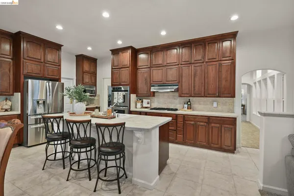 a kitchen with stainless steel appliances granite countertop a table chairs sink refrigerator and cabinets