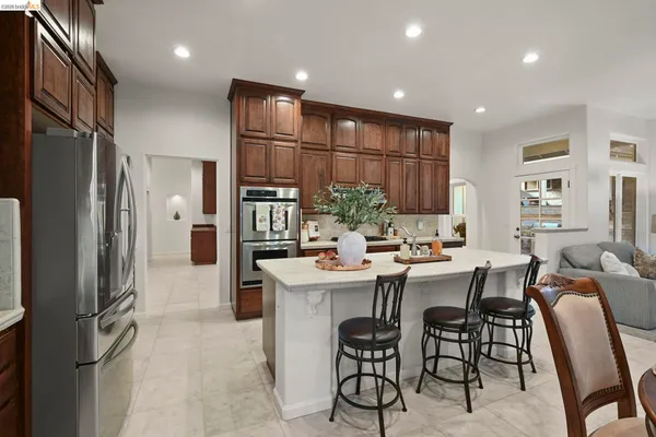 a kitchen with stainless steel appliances kitchen island granite countertop a refrigerator and a sink