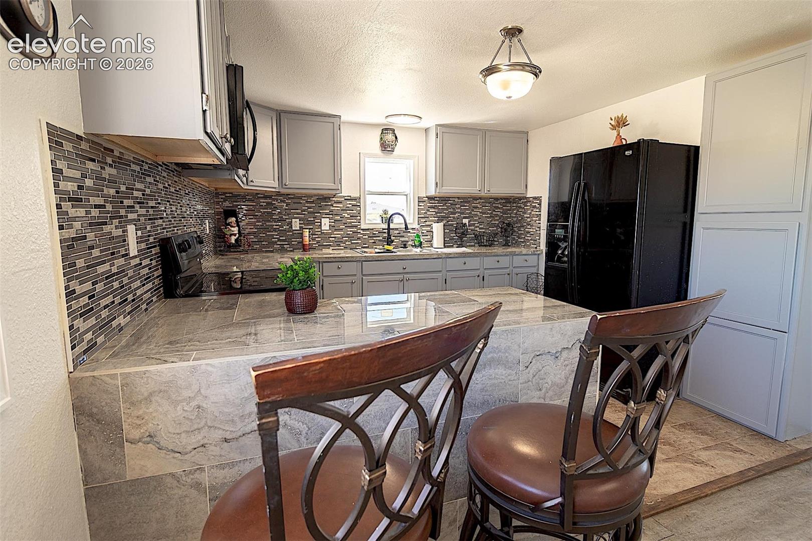 3425 Wiesner Road Calhan, CO 80808 - Photo 4 of 25 Kitchen featuring black appliances, a sink, decorative backsplash, light countertops, and gray cabinetry