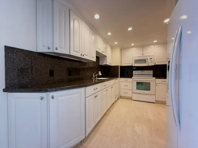 a kitchen with granite countertop white cabinets and stainless steel appliances