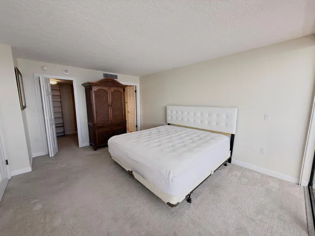 a spacious bedroom with a bed and a refrigerator