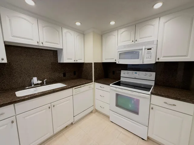 a kitchen with granite countertop white cabinets and white appliances