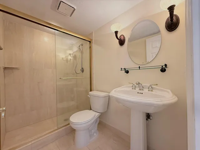 a bathroom with a sink a mirror a toilet and shower